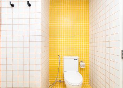 Modern bathroom with yellow and white tiling and toilet