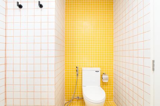 Modern bathroom with yellow and white tiling and toilet