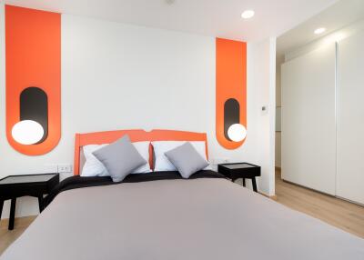 Modern bedroom with orange accents and bed with gray linens