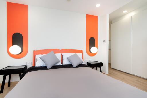 Modern bedroom with orange accents and bed with gray linens