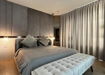 Modern bedroom with king-size bed, grey tones, and ample lighting