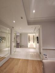 Modern hallway with white walls and ceiling, recessed lighting, mirrored walls, and wooden flooring