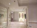 Modern hallway with white walls and ceiling, recessed lighting, mirrored walls, and wooden flooring