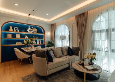 Cozy and modern living room with sofa, coffee table, dining area, bookshelves, and large windows