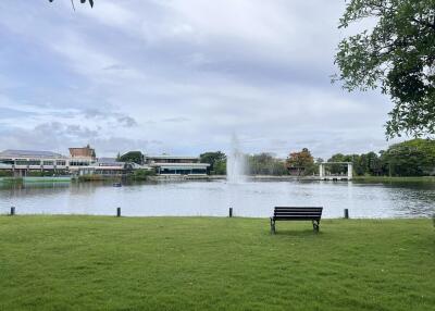 View of a park with a bench, fountain, and buildings in the background