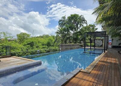 Outdoor pool area with wooden decking and lush greenery