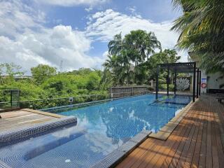 Outdoor pool area with wooden decking and lush greenery