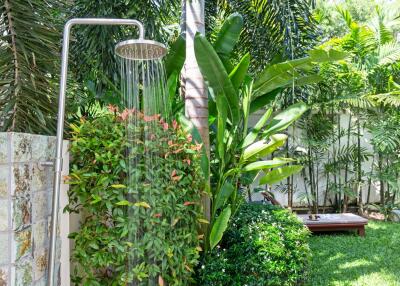 Outdoor shower surrounded by lush greenery