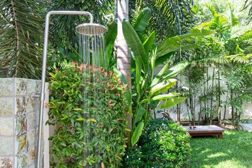 Outdoor shower surrounded by lush greenery