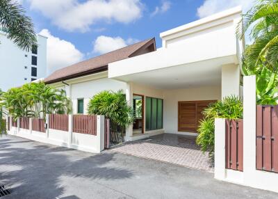 Exterior view of a modern house with a driveway and tropical plants