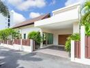 Exterior view of a modern house with a driveway and tropical plants