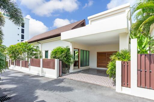 Exterior view of a modern house with a driveway and tropical plants