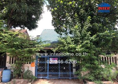 Front view of a house with greenery and a gated entrance