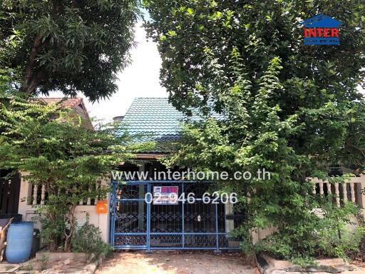 Front view of a house with greenery and a gated entrance