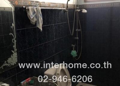 Bathroom with dark tile walls and white fixtures