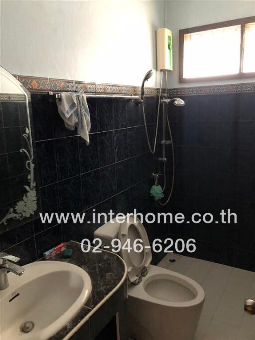 Bathroom with dark tile walls and white fixtures