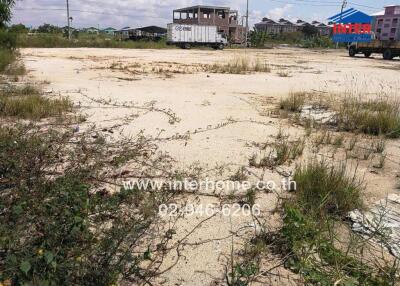 Vacant land with sparse vegetation and surrounding buildings