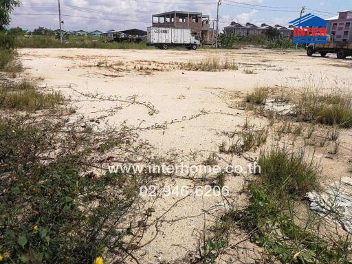 Vacant land with sparse vegetation and surrounding buildings