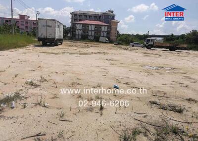 Vacant land with vehicles and a building in the background