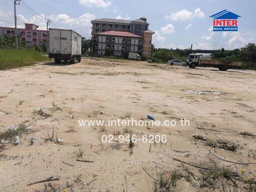 Vacant land with vehicles and a building in the background