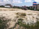 Open land plot with grass and a few vehicles in the background