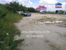 Empty plot with parked vehicles near a building