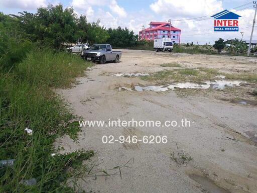 Empty plot with parked vehicles near a building