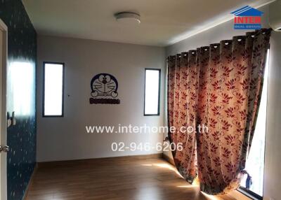 Bedroom with wooden floor, floral curtains, and two narrow windows