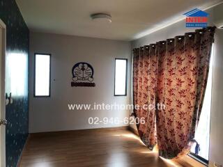 Bedroom with wooden floor, floral curtains, and two narrow windows