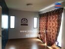 Bedroom with wooden floor, floral curtains, and two narrow windows