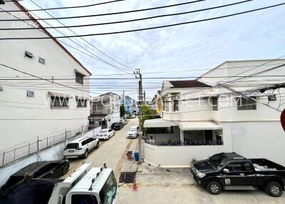 Street view of residential buildings with multiple parked vehicles