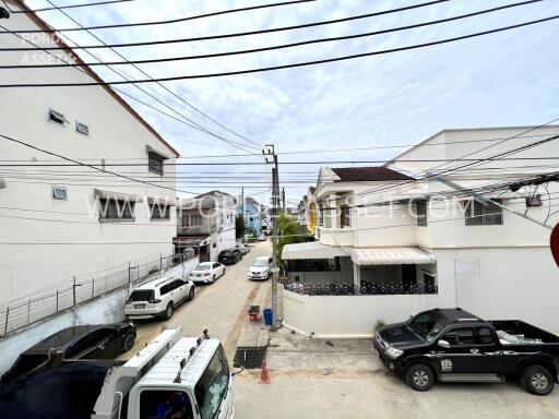 Street view of residential buildings with multiple parked vehicles