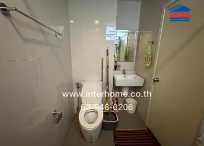 Modern bathroom with toilet, sink, and cleaning supplies