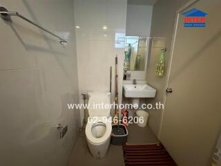 Modern bathroom with toilet, sink, and cleaning supplies