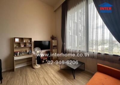 Modern living room with large window, TV, cabinet, fan, and orange sofa