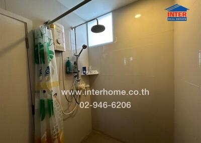 Modern bathroom shower area with water heater and a small window