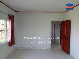 Bedroom with a window, red curtains, and a wooden door