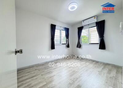 Spacious bedroom with wooden floor and large windows