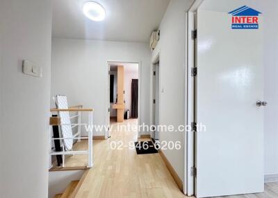 Hallway leading to various rooms with wooden flooring