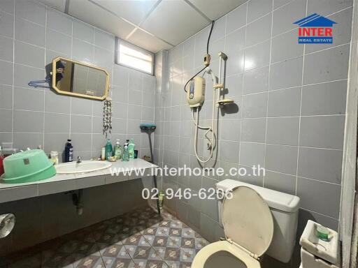 Bathroom with tiled walls and floor, a mirror, a sink, and a toilet