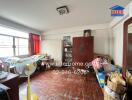 A bedroom with two beds, wooden flooring, a fan, cabinets, and various personal items.