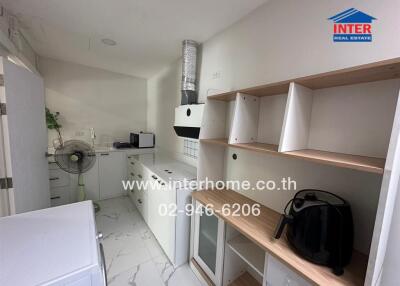 Modern kitchen with white cabinets, an extractor hood, counter appliances, and a fan