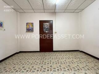 Empty bedroom with a wooden door and tiled floor