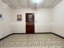 Empty bedroom with a wooden door and tiled floor