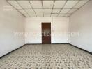 Spacious empty room with tiled floor and wooden door