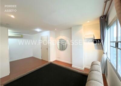 Modern living room with a large window, air conditioner, and hardwood flooring.