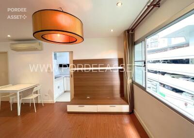 Modern living area with wooden flooring, large window, and adjacent kitchen