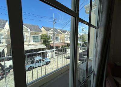 View from window showing neighborhood street with houses and cars