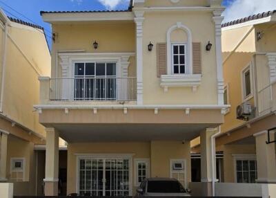 Two-story yellow house with a balcony, garage, and gated entrance