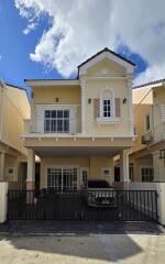 Two-story yellow house with a balcony, garage, and gated entrance